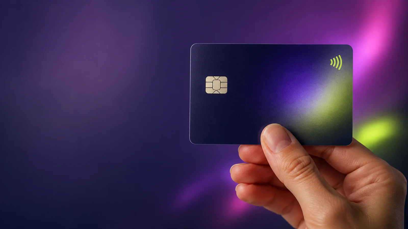 A hand holding one recognizable payment card with a visible chip and contactless symbol